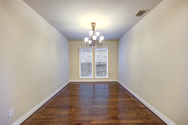 a view of a hallway with wooden floor and a chandelier