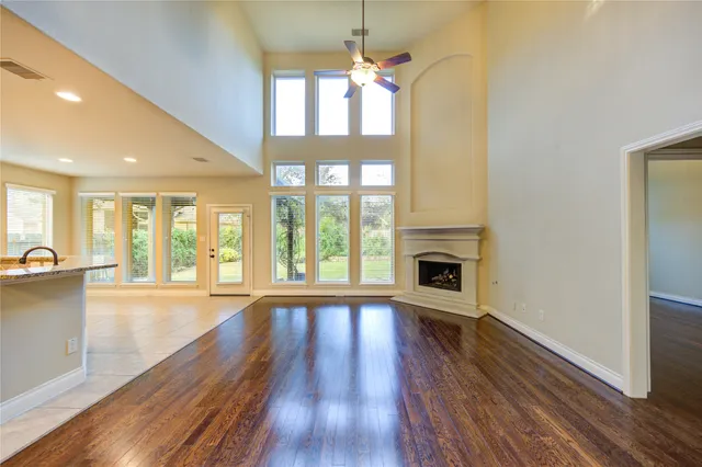 a view of an empty room with wooden floor fireplace and a window