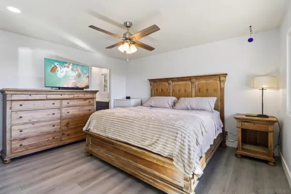 a bedroom with a bed a chandelier and a painting on the wall