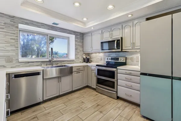 a kitchen with stainless steel appliances granite countertop a stove top oven a sink and a refrigerator
