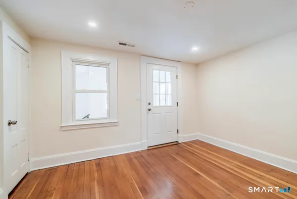 an empty room with wooden floor and windows