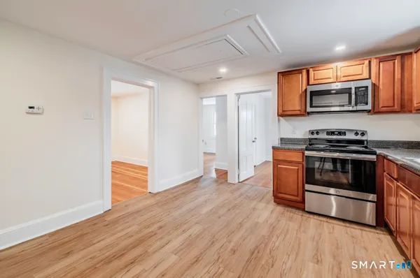 a view of kitchen with stainless steel appliances granite countertop a stove a sink and a microwave