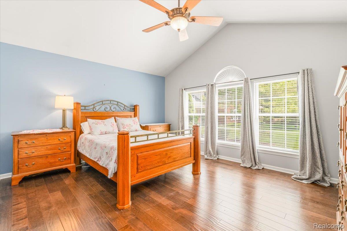 49105 Hawksburry Road Canton, MI 48188 - Photo 18 of 51 Vaulted ceiling with a ceiling fan, wood-finish flooring, and multiple windows with an arched transom