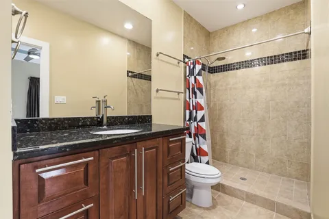 a bathroom with a granite countertop sink toilet a mirror and shower