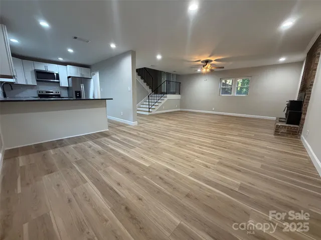 a view of large kitchen with kitchen island a sink stainless steel appliances and cabinets