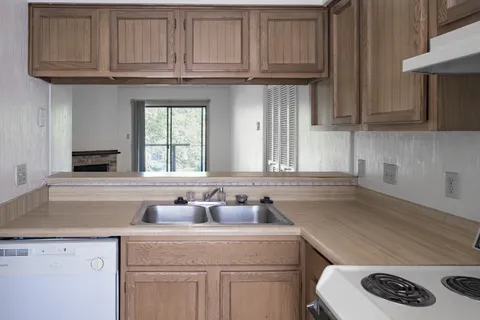 a kitchen with stainless steel appliances granite countertop a sink dishwasher a stove and cabinets with wooden floor