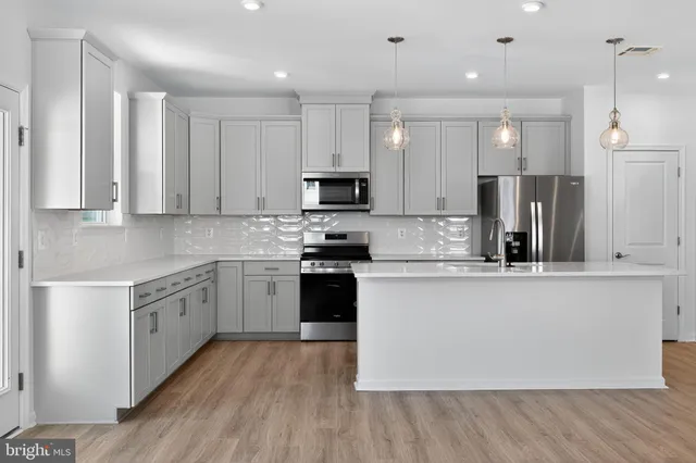 a kitchen with stainless steel appliances granite countertop a stove top oven a sink and white cabinets