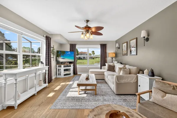 a living room with furniture a flat screen tv and a floor to ceiling window