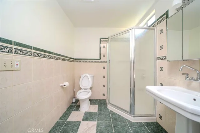 a bathroom with a sink a toilet a mirror and shower