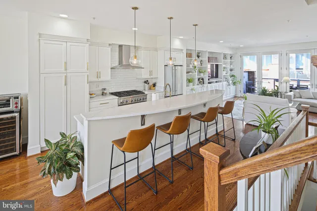 a kitchen with stainless steel appliances kitchen island granite countertop a refrigerator a stove a sink a dining table and chairs with wooden floor