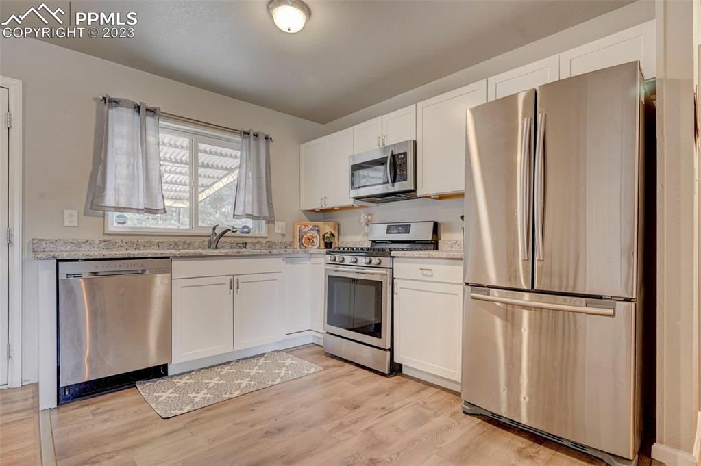 113 Kiva Road Colorado Springs, CO 80911 - Photo 6 of 12 a kitchen with white cabinets stainless steel appliances and window