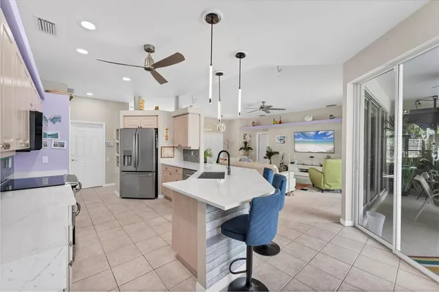 a kitchen with stainless steel appliances kitchen island granite countertop a refrigerator a sink a stove and white cabinets