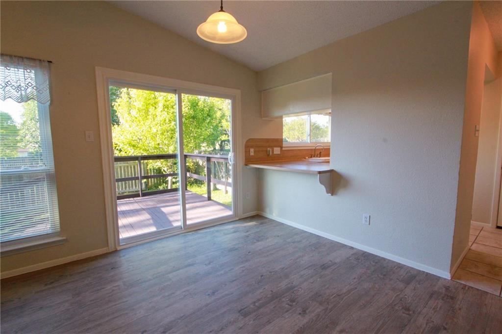 12902 Old San Antonio Road, Unit A Manchaca, TX 78652 - Photo 5 of 9 Living area featuring wood-finish flooring, vaulted ceilings, and a sliding glass door opening to a private deck
