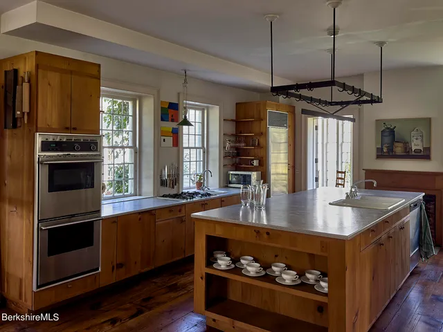a kitchen with stainless steel appliances granite countertop a sink a stove and a wooden floors