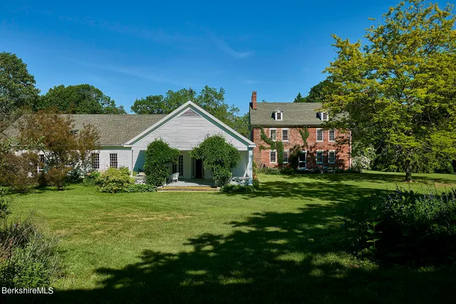 a view of a brick house with a large window and potted plants