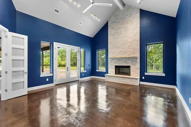 a view of an empty room with window wooden floor and a kitchen view