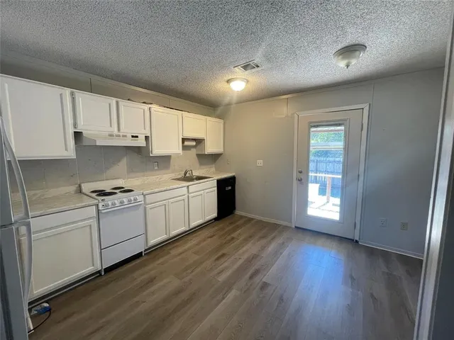a kitchen with wooden floors and white appliances