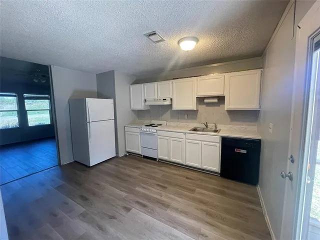 a kitchen with a refrigerator a stove top oven a sink a counter space and cabinets