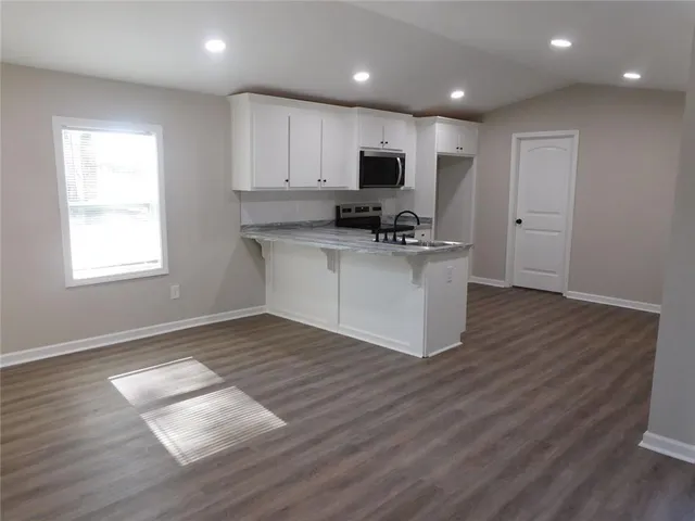a kitchen with kitchen island a sink wooden floor and white cabinets