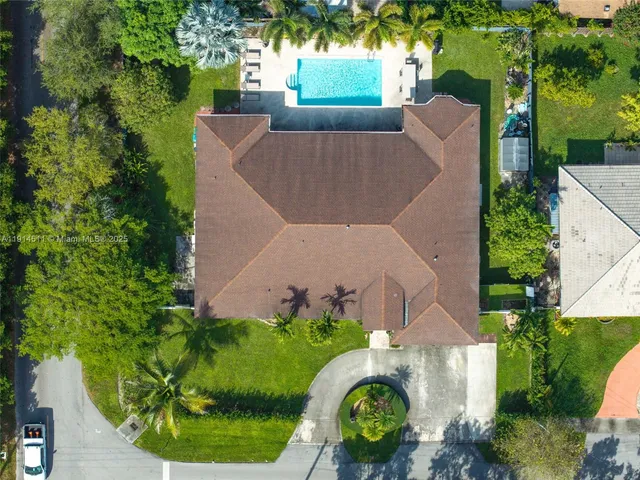 an aerial view of a house with outdoor space and trees all around