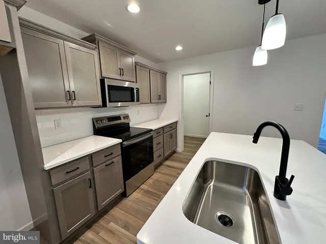 a kitchen with kitchen island granite countertop a sink stainless steel appliances and cabinets