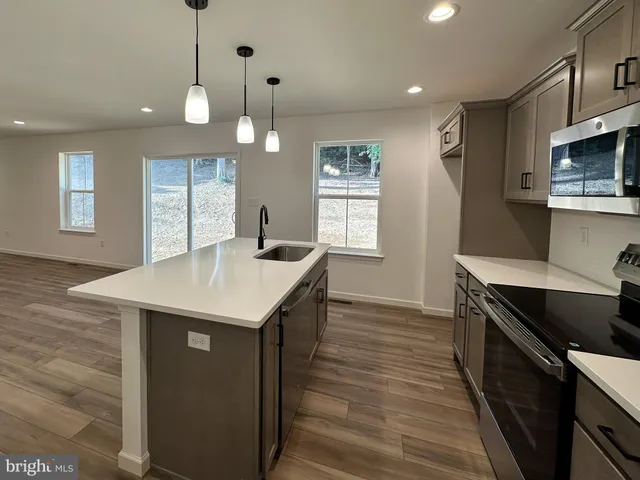 a kitchen with stainless steel appliances granite countertop a sink a stove and a wooden floors