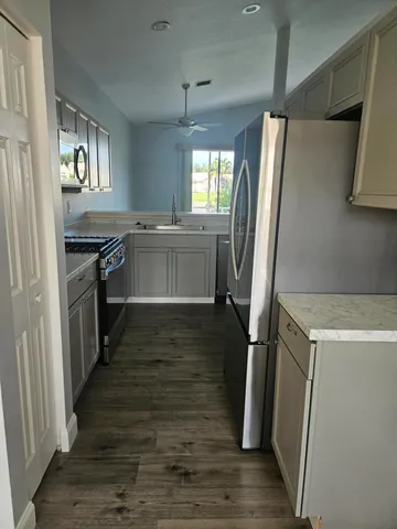 a kitchen with a refrigerator a sink and wooden floor
