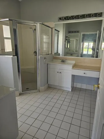 a spacious bathroom with a shower a mirror and a sink