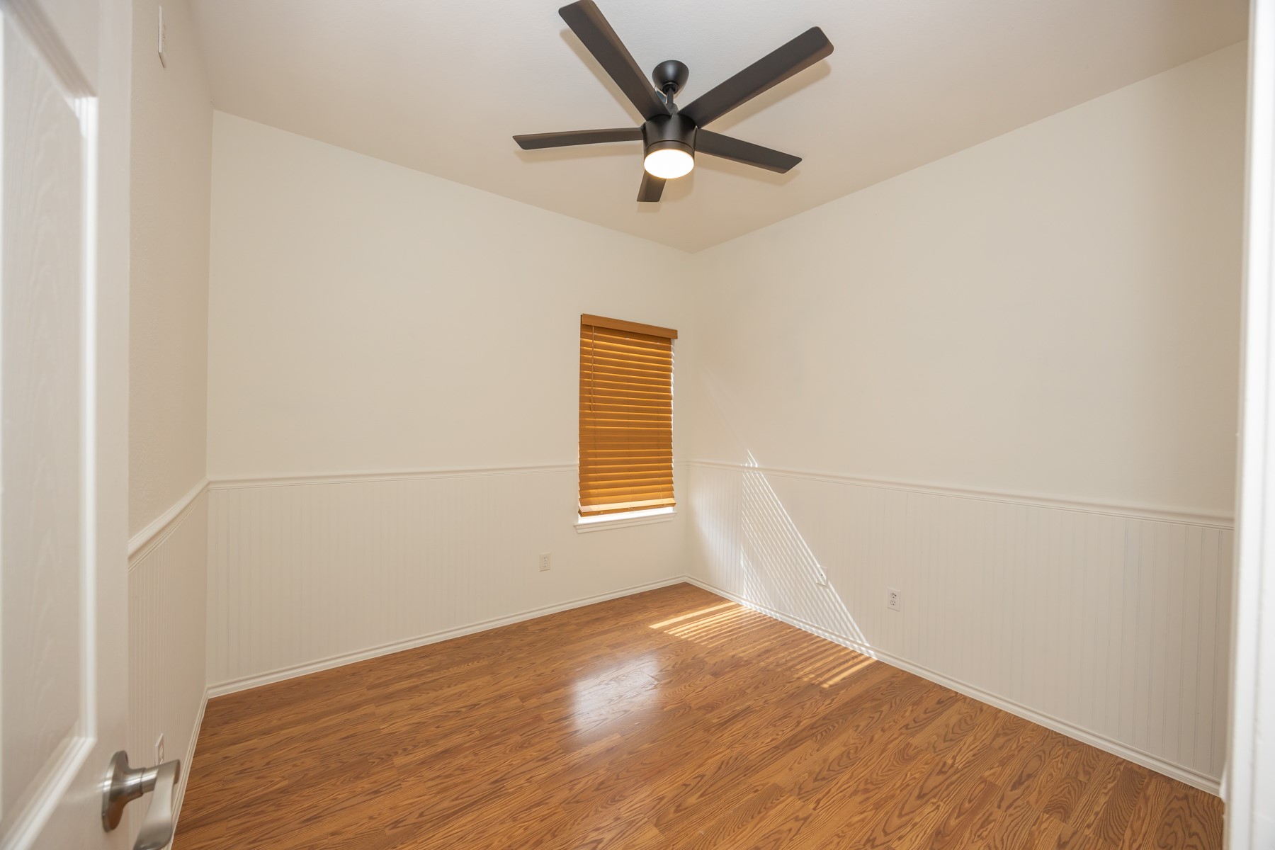 11500 Dimmit Street Manor, TX 78653 - Photo 12 of 14 Room featuring wood-finish flooring, a window with wood blinds, and wainscoting
