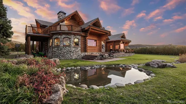 a front view of a house with a garden and lake view