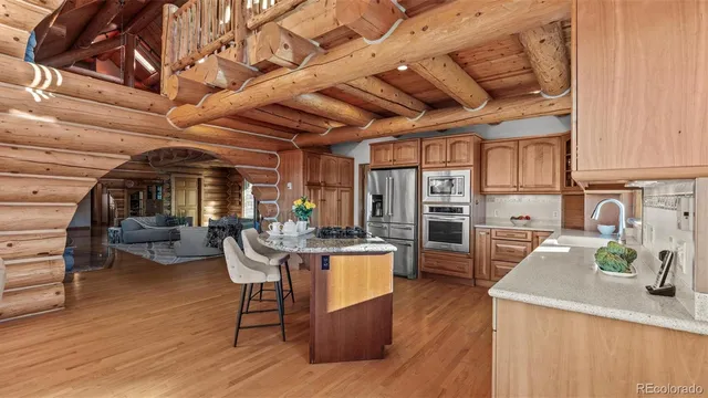 a living room with stainless steel appliances kitchen island granite countertop wooden floors and a stove
