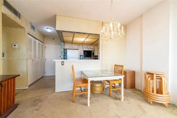 a room with stainless steel appliances kitchen island granite countertop furniture and a chandelier