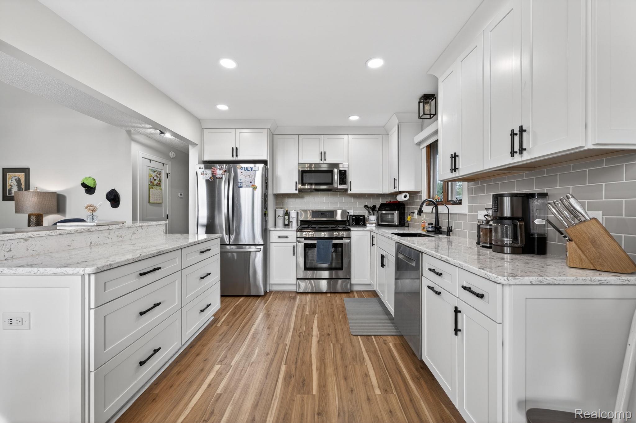 1280 Petts Road Fenton, MI 48430 - Photo 14 of 62 Kitchen with white cabinets, stainless steel appliances, light stone counters, light wood finished floors, and recessed lighting