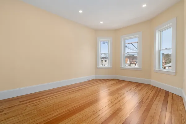 an empty room with wooden floor and windows