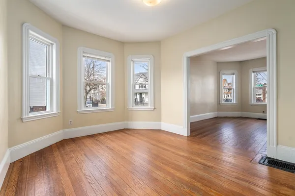 an empty room with wooden floor and windows