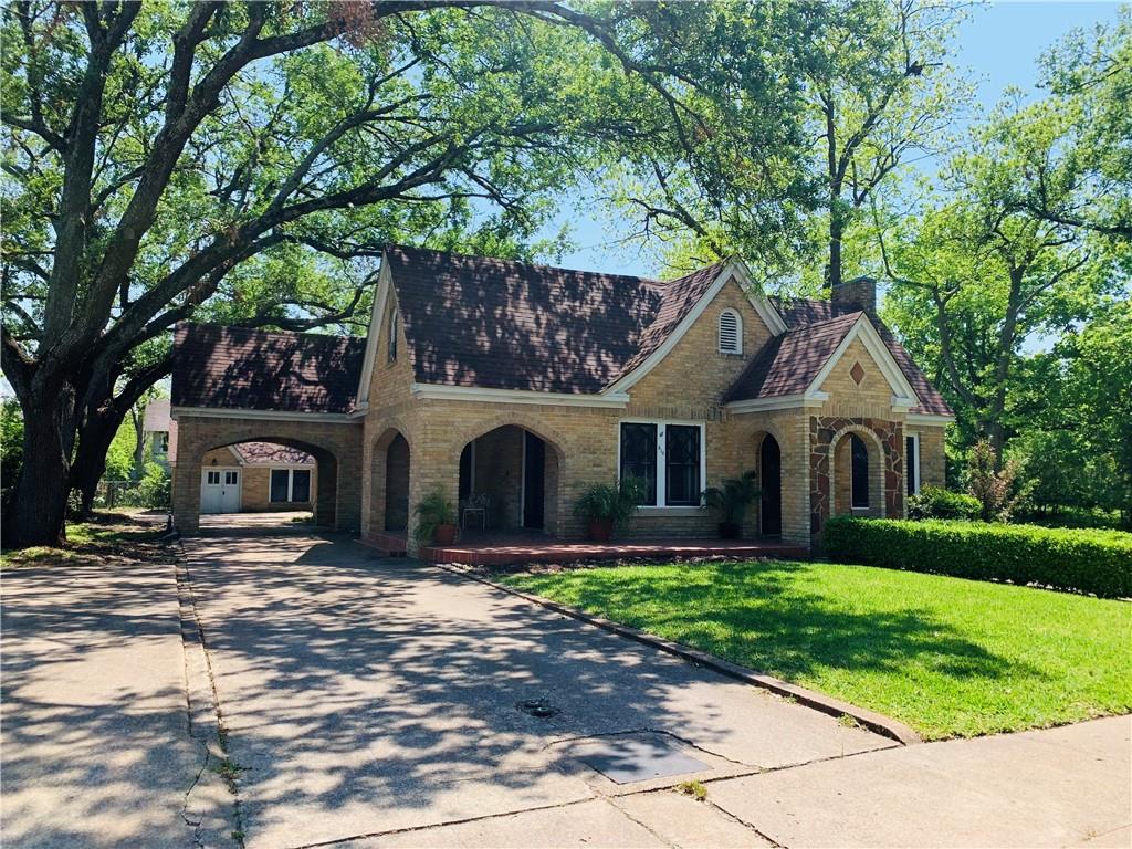 a front view of a house with a garden and trees