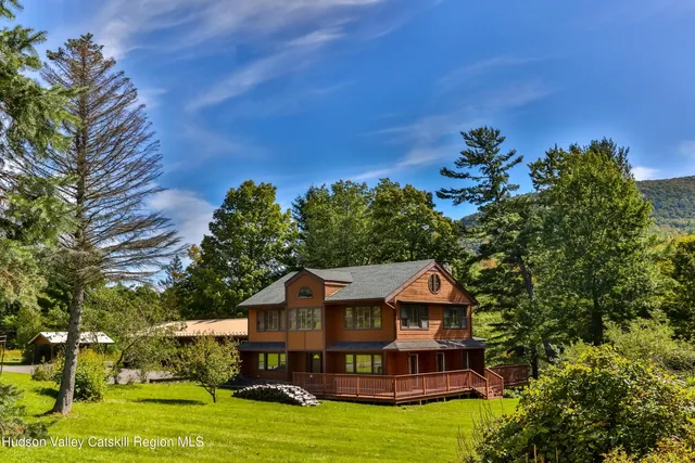 a view of a house with a big yard plants and large trees
