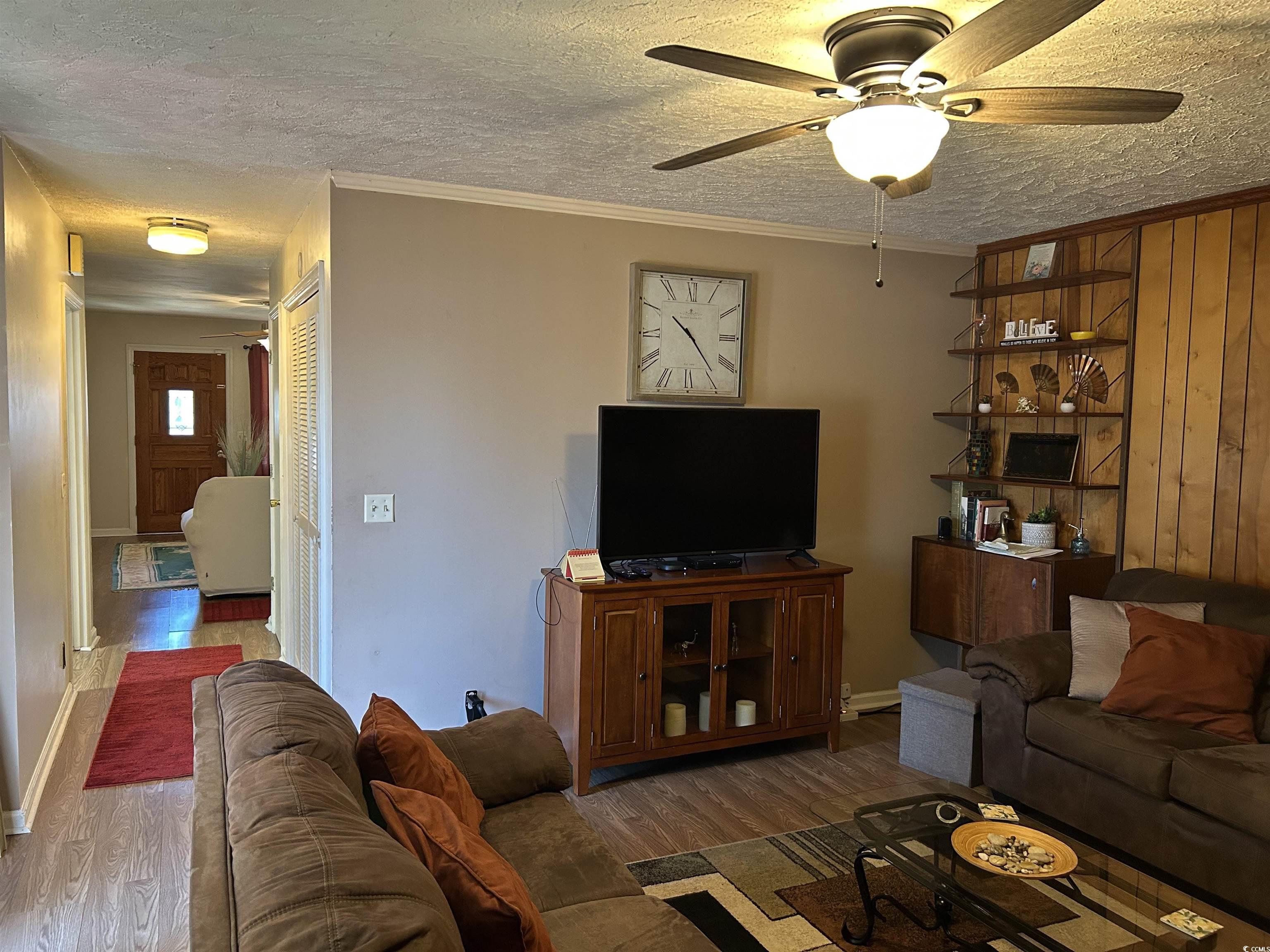 1411 East Harrison Street Dillon, SC 29536 - Photo 19 of 40 Living area featuring a textured ceiling, ceiling fan, crown molding, and wood finished floors