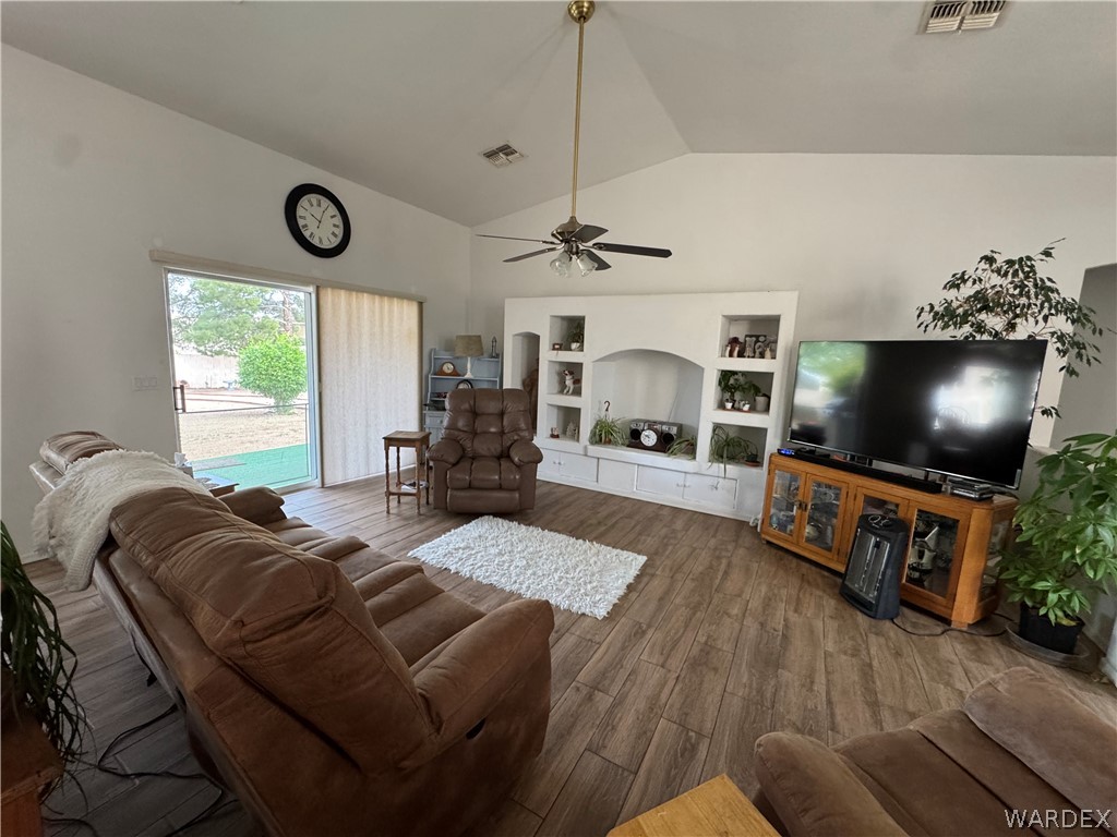4029 Roma Road Kingman, AZ 86401 - Photo 12 of 90 The living room features vaulted ceilings, wood-look flooring, and a built-in entertainment center with shelving