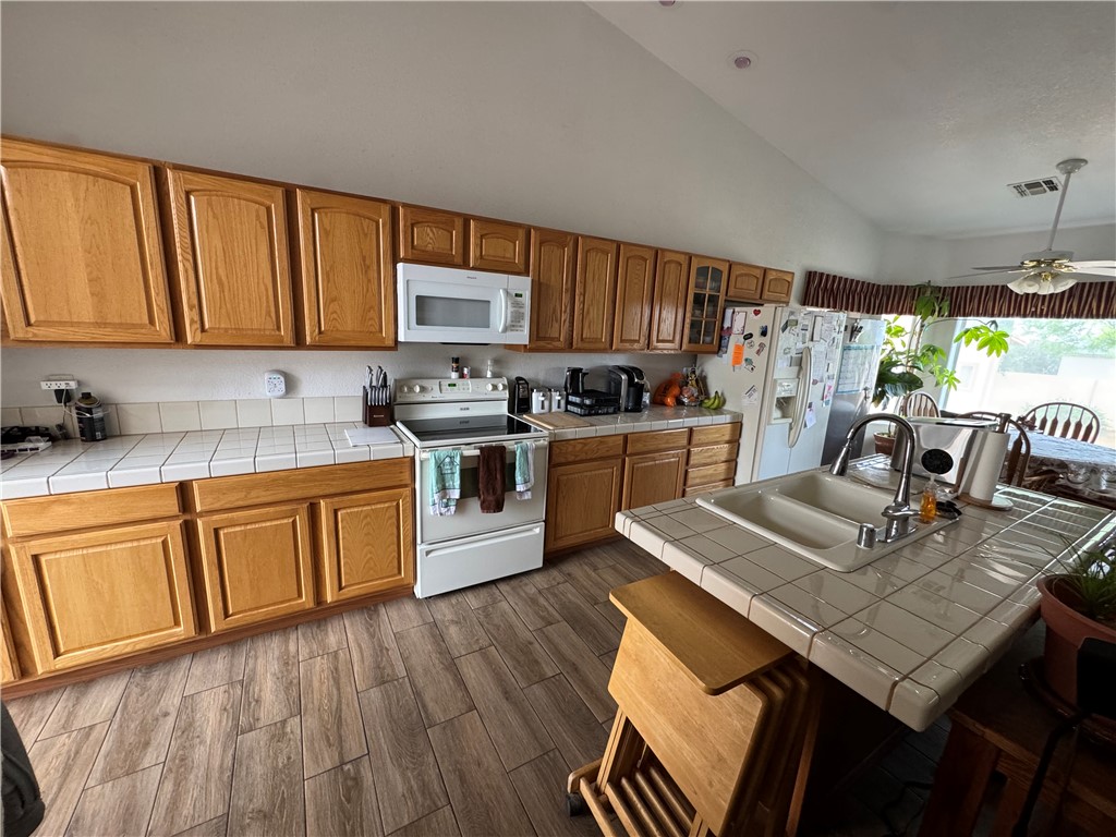 4029 Roma Road Kingman, AZ 86401 - Photo 17 of 90 This kitchen features extensive wood cabinetry, white tile countertops, and a white tile backsplash