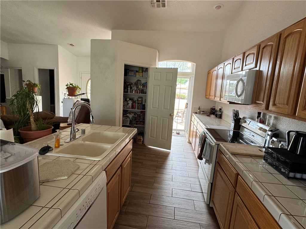 4029 Roma Road Kingman, AZ 86401 - Photo 18 of 90 The kitchen features extensive tile countertops, a double basin sink, and a range with an overhead microwave