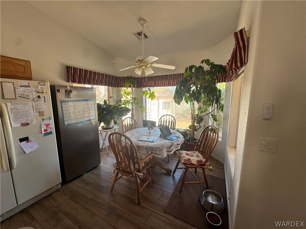 4029 Roma Road Kingman, AZ 86401 - Photo 19 of 90 This dining area features large windows, wood-look flooring, and a ceiling fan