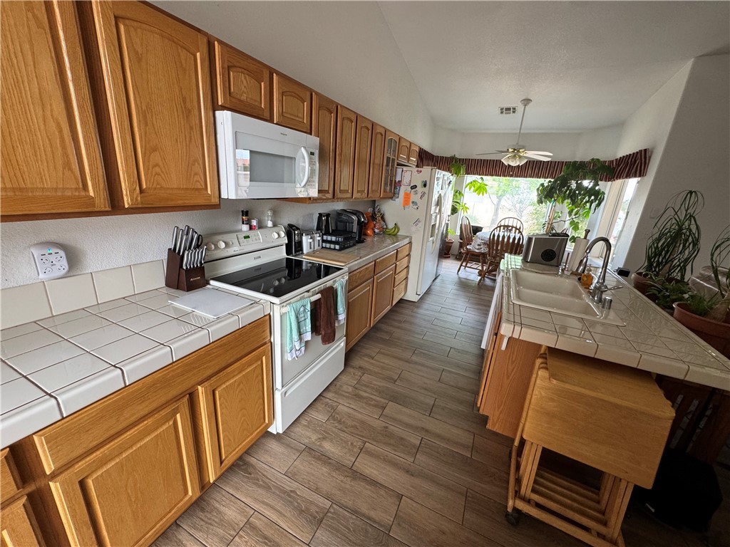 4029 Roma Road Kingman, AZ 86401 - Photo 23 of 90 The kitchen features wood cabinetry, tile countertops, and a white electric range