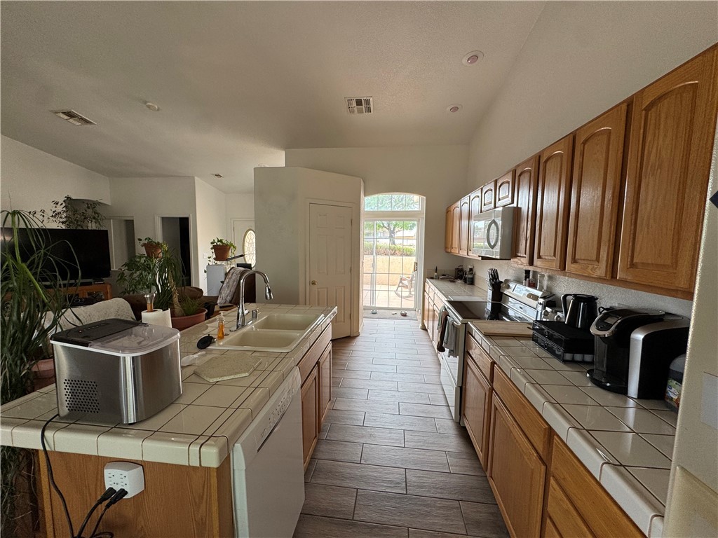 4029 Roma Road Kingman, AZ 86401 - Photo 24 of 90 Well-appointed kitchen featuring wood cabinetry, tile countertops, a double basin sink, and an oven with an overhead microwave
