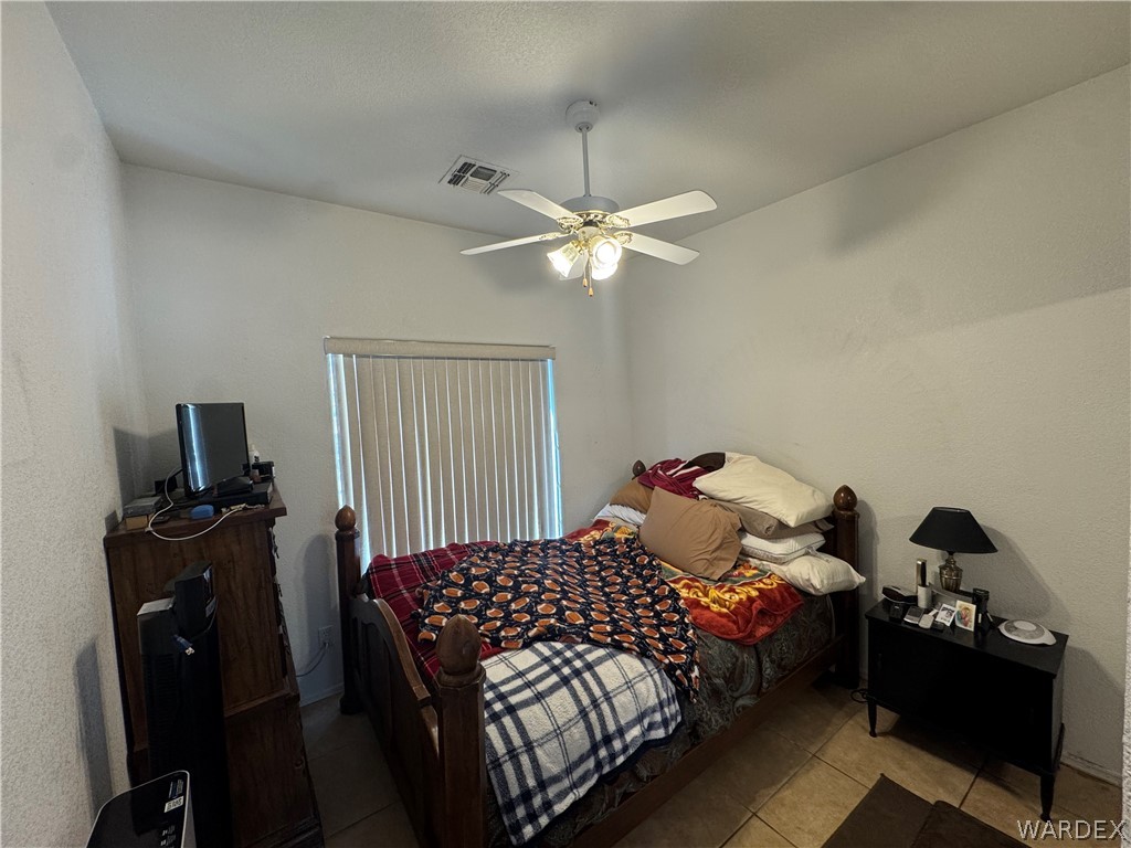 4029 Roma Road Kingman, AZ 86401 - Photo 27 of 90 This room features a ceiling fan with integrated lighting, a window with vertical blinds, and tile flooring