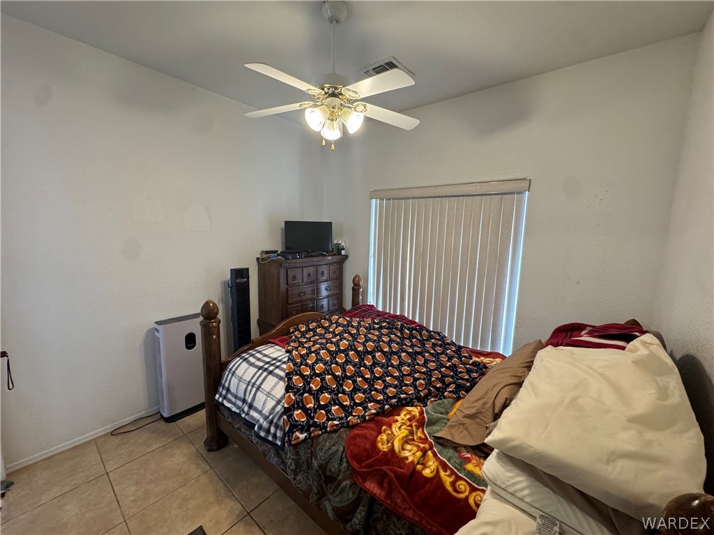 4029 Roma Road Kingman, AZ 86401 - Photo 28 of 90 This room features tiled flooring, a ceiling fan with integrated lighting, and a window with vertical blinds