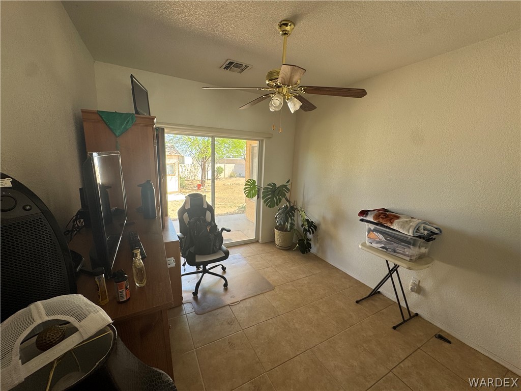 4029 Roma Road Kingman, AZ 86401 - Photo 34 of 90 This room features tiled flooring, a ceiling fan with integrated lighting, and a sliding glass door providing direct access to the outdoor area