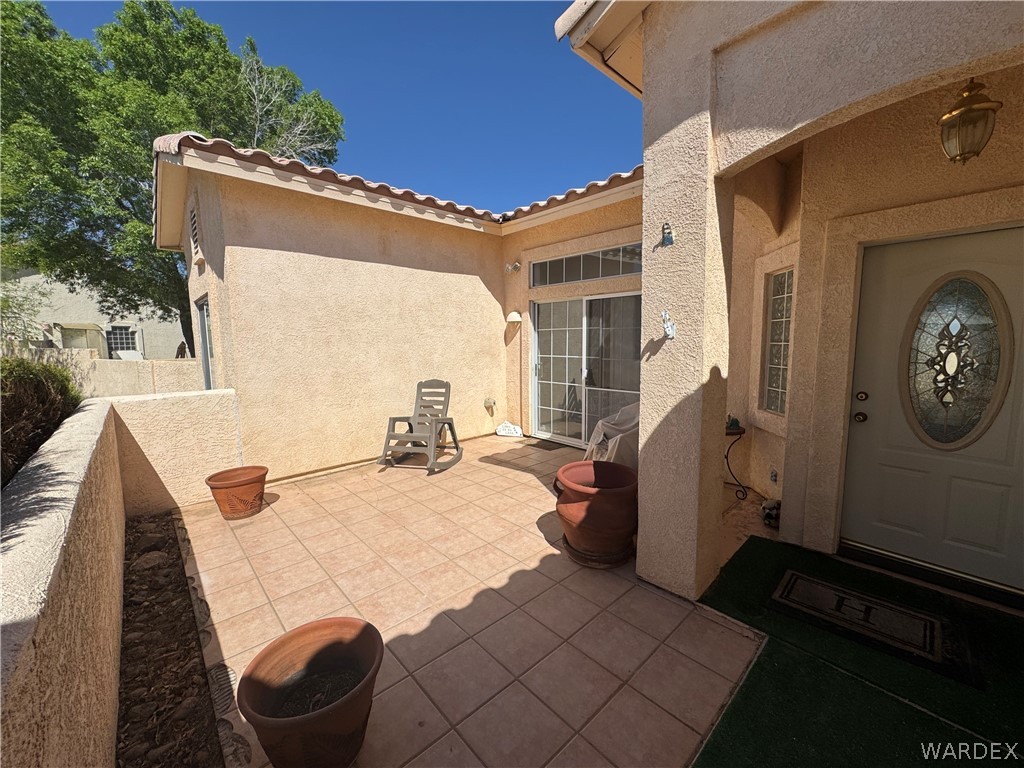 4029 Roma Road Kingman, AZ 86401 - Photo 44 of 90 A welcoming tiled patio area provides outdoor living space, featuring a sliding glass door and a front door with an oval decorative glass insert