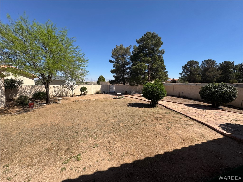 4029 Roma Road Kingman, AZ 86401 - Photo 48 of 90 The property features an expansive yard with a stone pathway, mature trees, and shrubbery