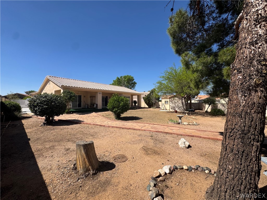 4029 Roma Road Kingman, AZ 86401 - Photo 58 of 90 The property features an extensive yard with a brick pathway, mature trees, and a detached shed